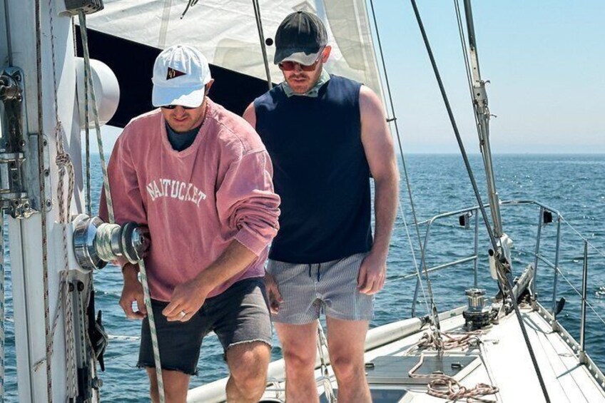 Two people on a sailboat with a clear view of the ocean. 5