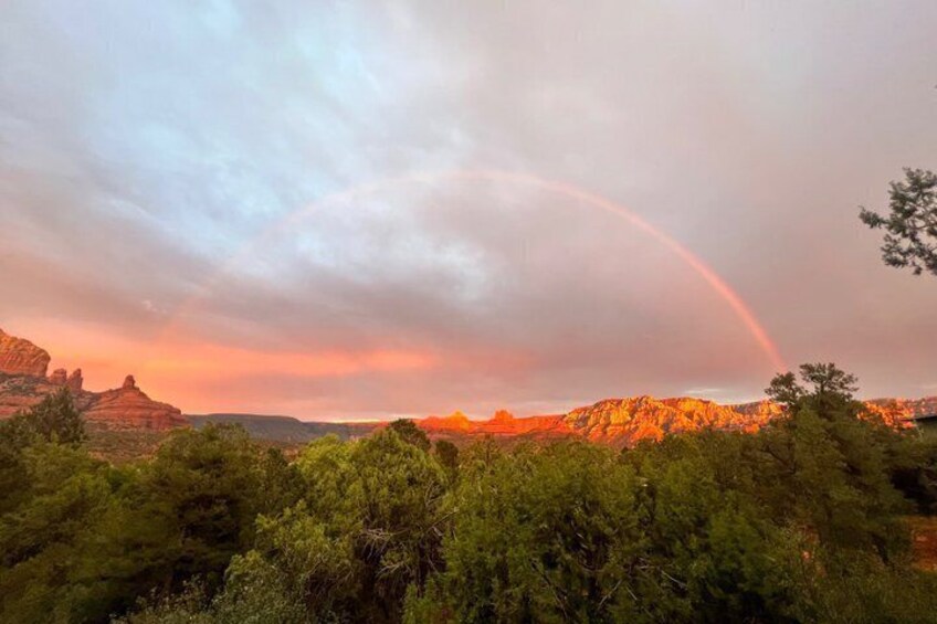 A landscape with a rainbow, mountains, and dense green foliage. 2
