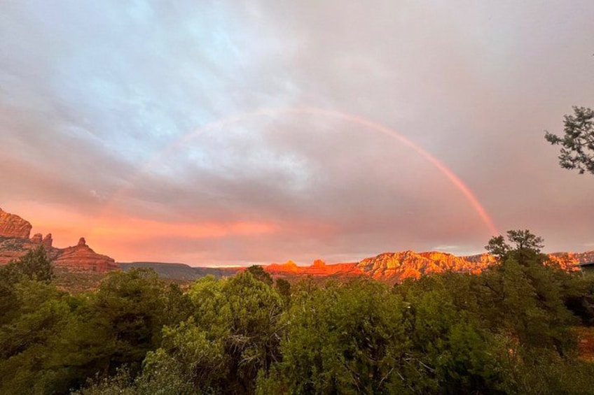 A landscape with a rainbow, mountains, and dense green vegetation. 2