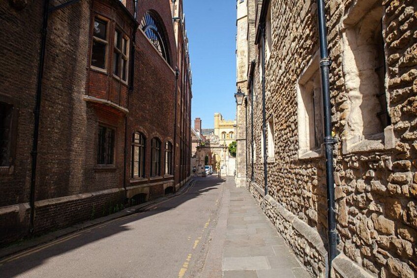 A narrow street flanked by historic buildings with stone walls and brick facades. 3