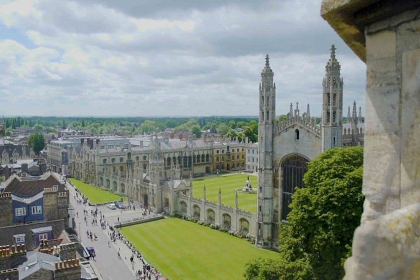 A historic university campus with a large lawn, Gothic architecture, and a prominent clock tower. 1