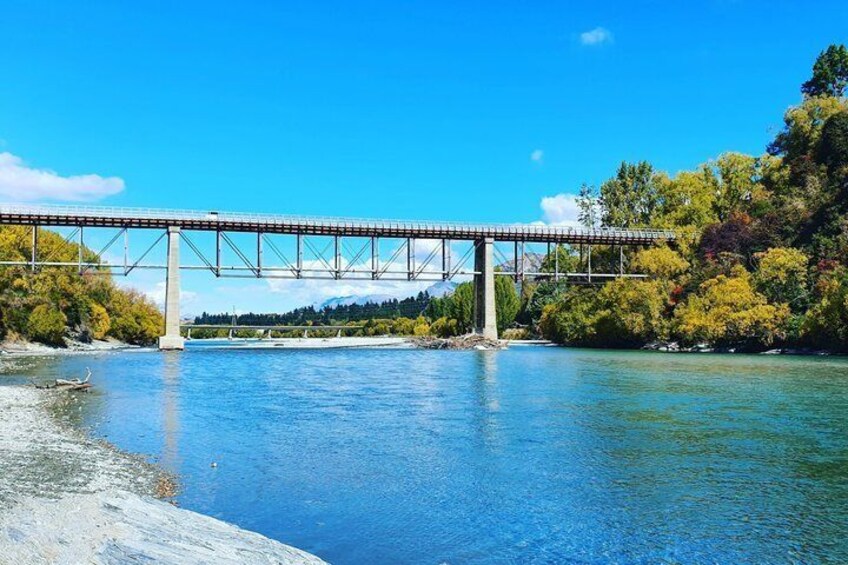A bridge over a river with trees and a clear sky. 3