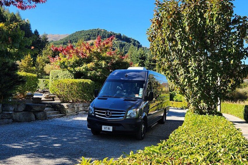 A black Mercedes van parked on a gravel driveway surrounded by lush greenery and trees. 3