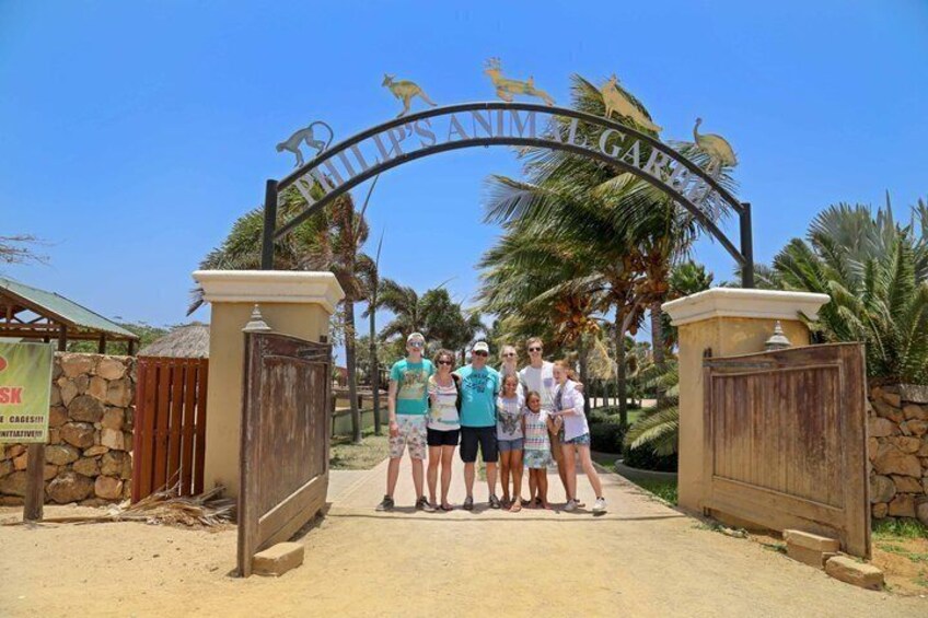 A family at the entrance of Philip's Gardens with a sign featuring a kangaroo and palm trees. 1
