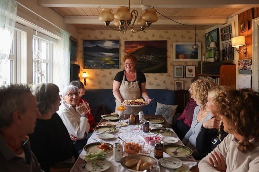 A group of people dining at a table with a person serving food. 1