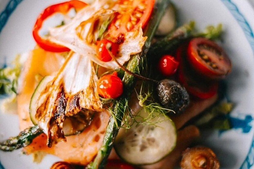 A salad with grilled chicken, cherry tomatoes, cucumber slices, and a drizzle of dressing. 2