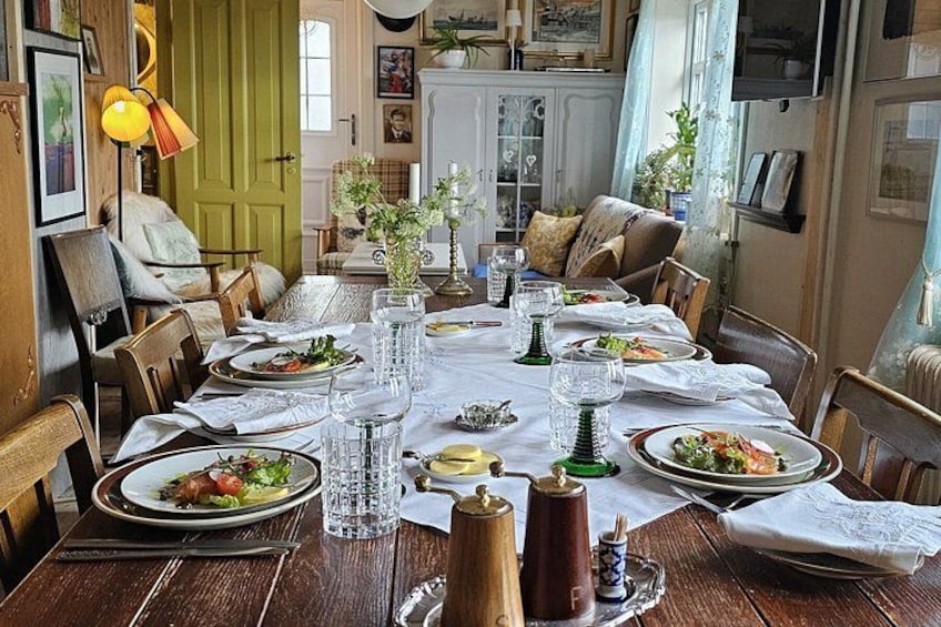 A wooden dining table set with plates, glasses, and a pitcher. 2