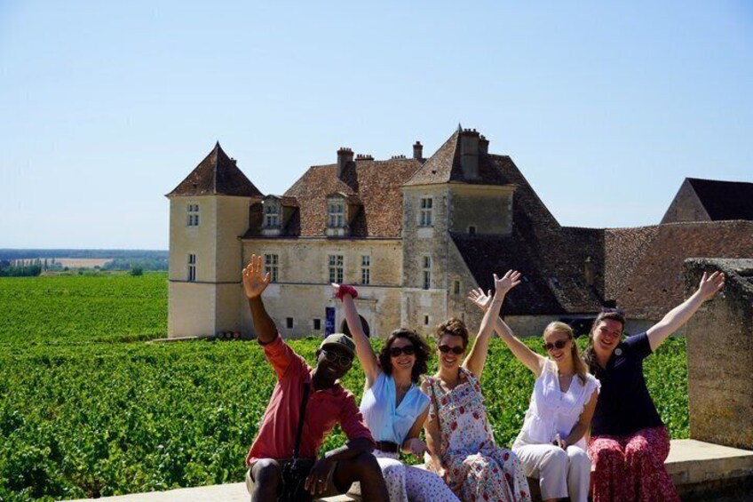 A group of people sitting on a ledge with a castle in the background. 1