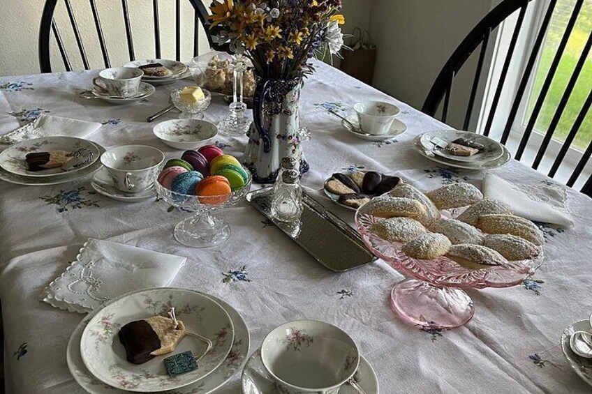 A table set with various dishes, including macarons, pastries, and a vase with flowers. 2
