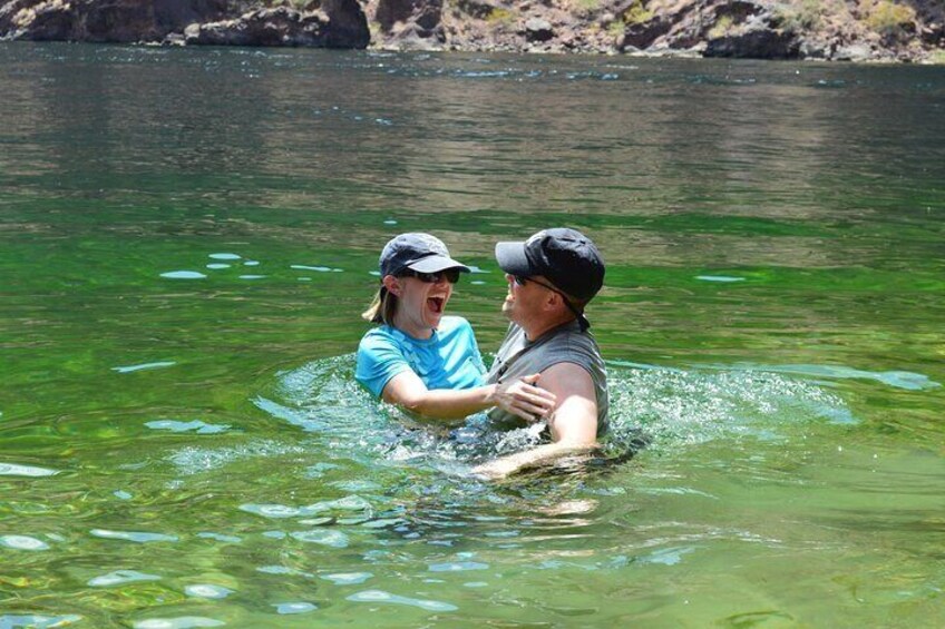 Deux personnes nagent dans une rivière aux eaux claires, entourée d’un paysage rocheux. 4