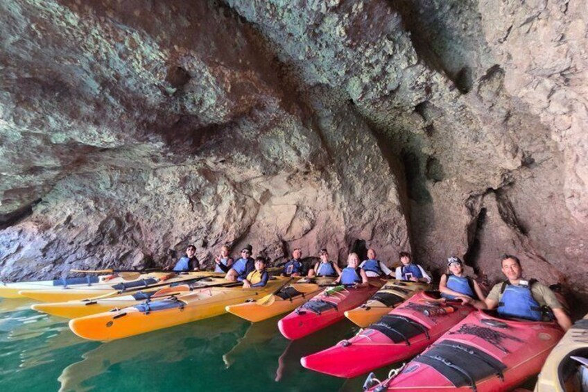 People sitting on kayaks inside a cave. 5