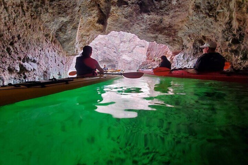 Des personnes pratiquent le kayak dans une grotte où l’eau est verte. 2