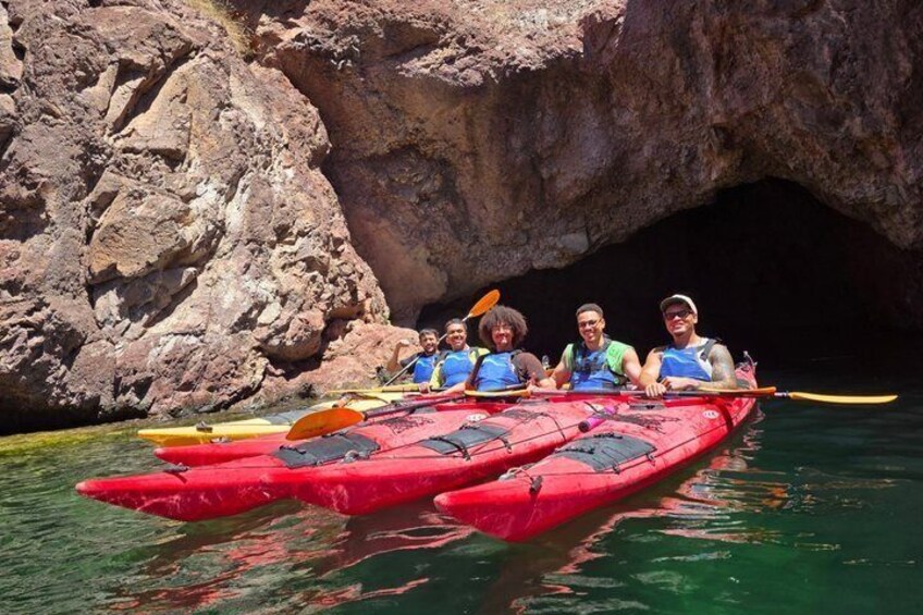A group of people kayaking in a red kayak through a rocky waterway. 2