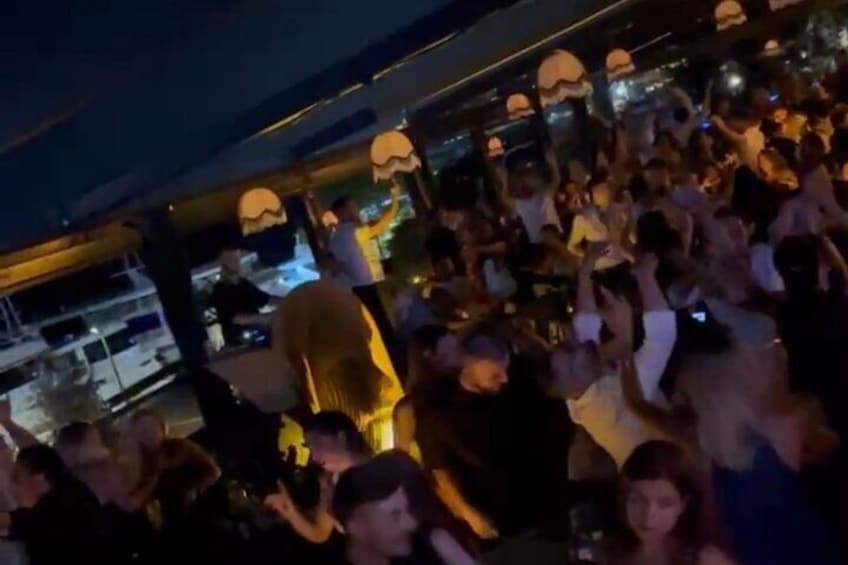 A crowded outdoor event with people gathered under a canopy. 2