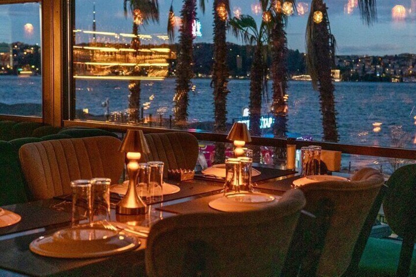 A table set for dining with a view of a waterfront cityscape at dusk. 1