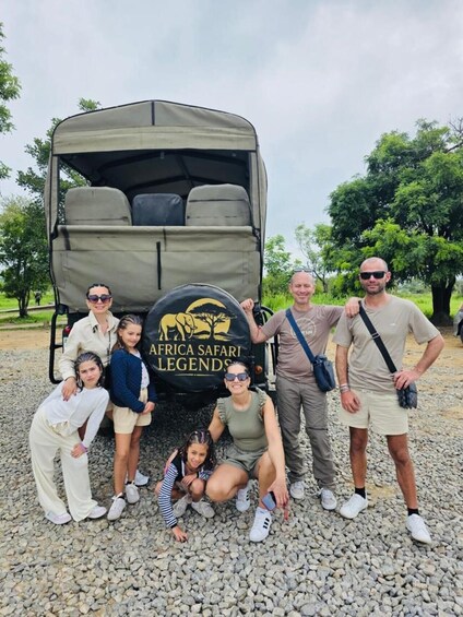A group of people posing in front of a safari vehicle with a logo that reads 'AFRICA SAFARI LEGENDS'. 4
