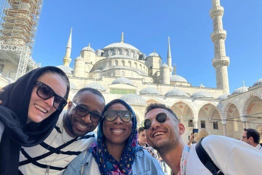 A group of people taking a selfie in front of a historic mosque with domes and minarets. 1
