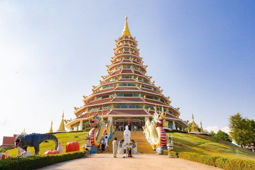 A multi-tiered temple with a golden spire, surrounded by statues and lush greenery. 1