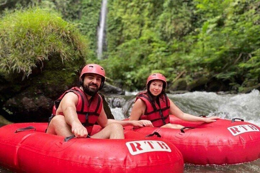 Two people in red inflatable rafts on a river surrounded by greenery. 5