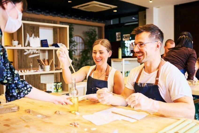 A person preparing food at a counter with a bottle and utensils. 1