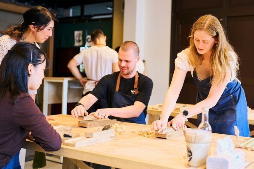 A group of people engaged in a cooking activity around a wooden table with various kitchen tools and ingredients. 4