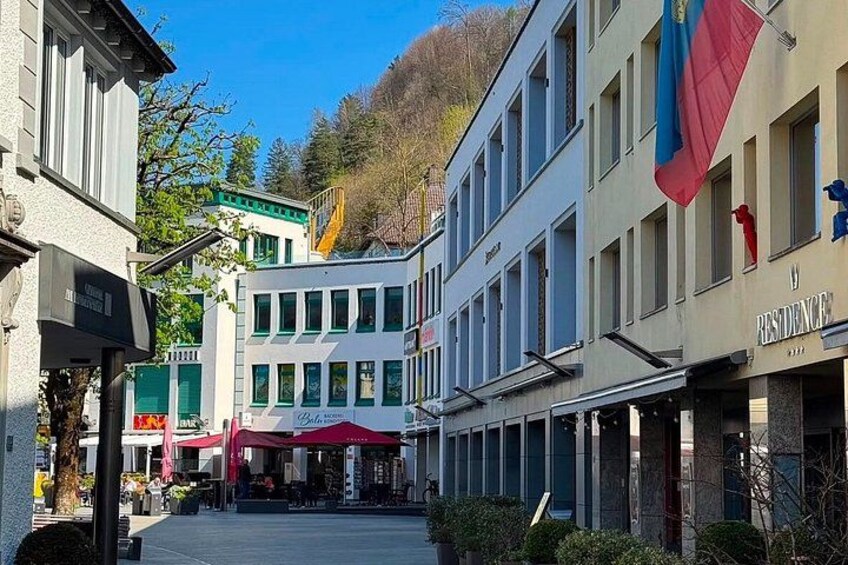 A street with buildings, a flag, and a sign for a residence. 4