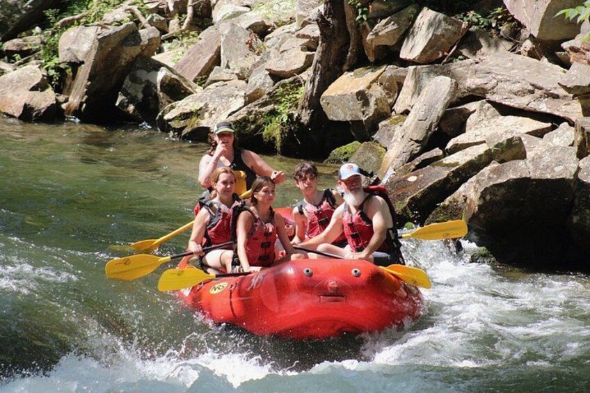 A group of people in a red raft navigating a river surrounded by rocks. 3