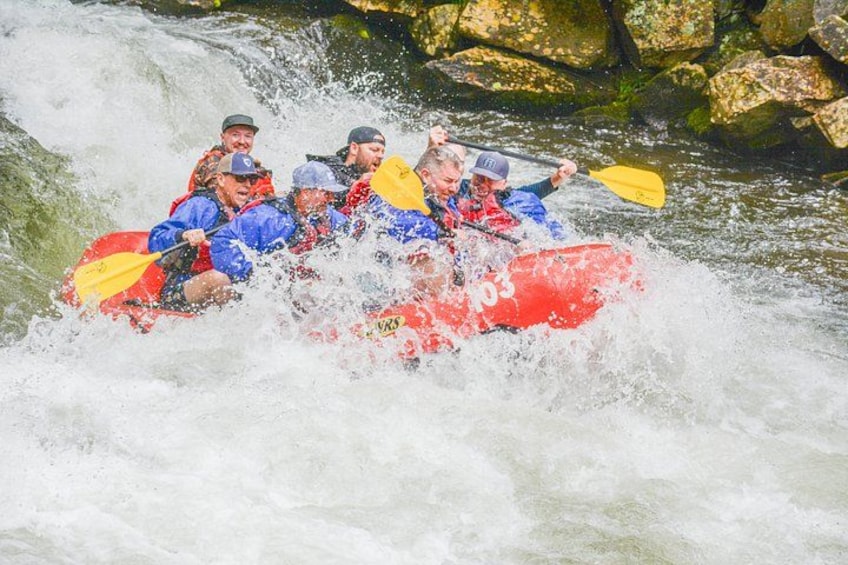 A group of people in a red raft navigating a river rapids. 3