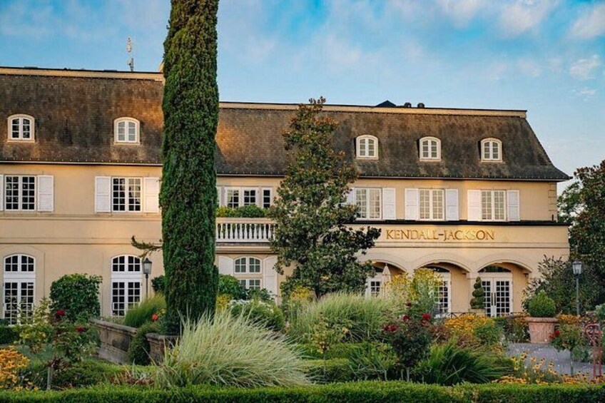 A historic building with 'KENDALL-JACKSON' signage, surrounded by lush gardens and a tall tree. 4
