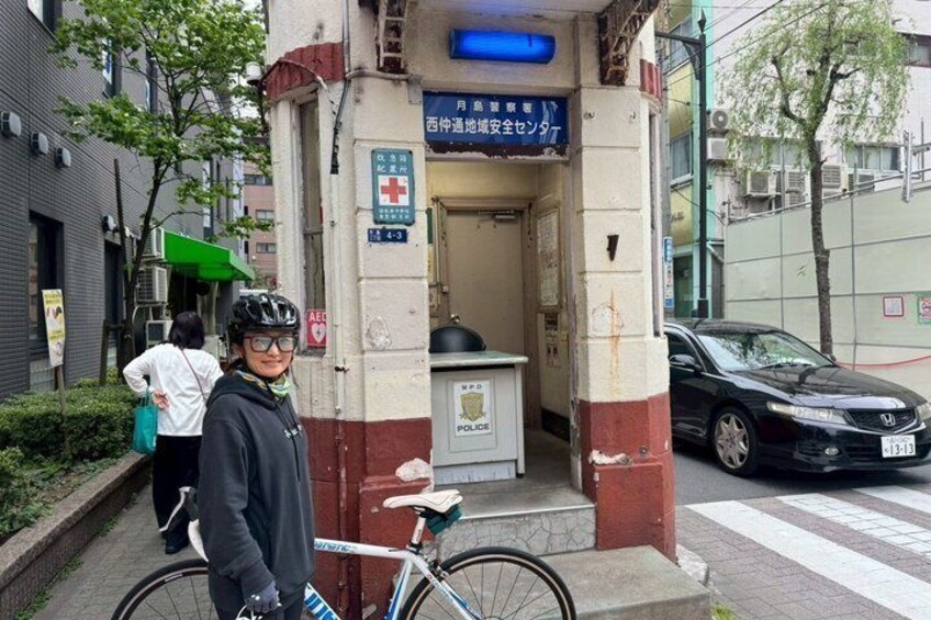 A person standing next to a bicycle in front of a medical facility with a red cross sign. 5