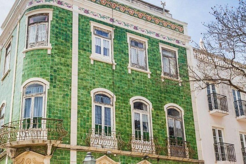 A building with green mosaic tiles, multiple windows, and balconies. 2