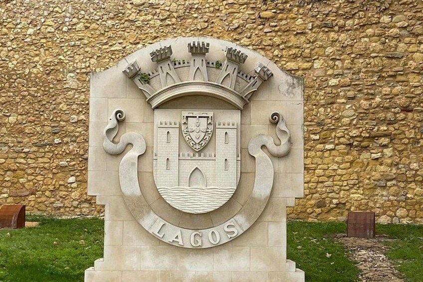 A stone monument with a coat of arms and the word 'LAGOS' at the base. 4