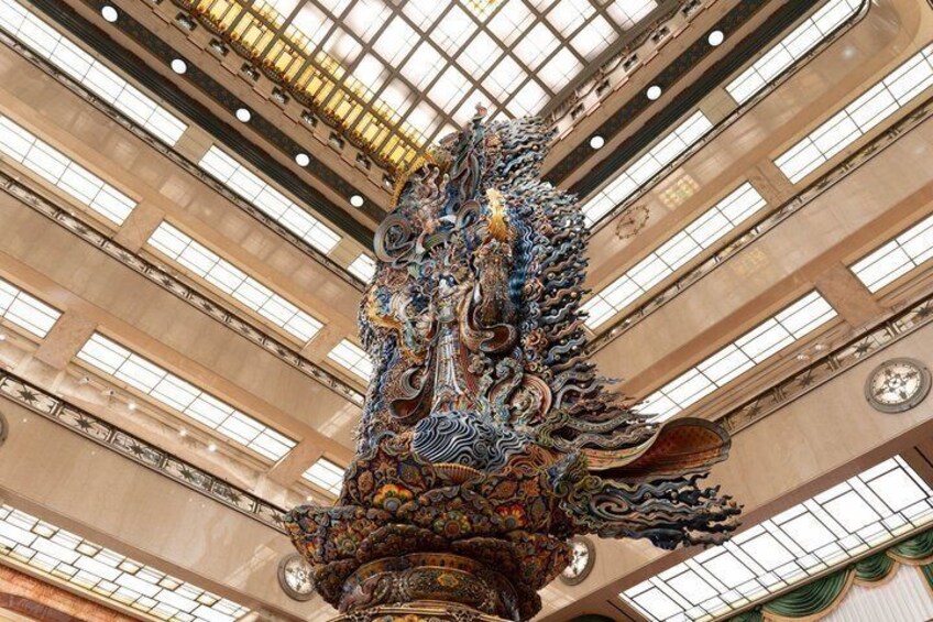 A large, ornate dragon sculpture in an indoor space with a high ceiling and multiple windows. 2