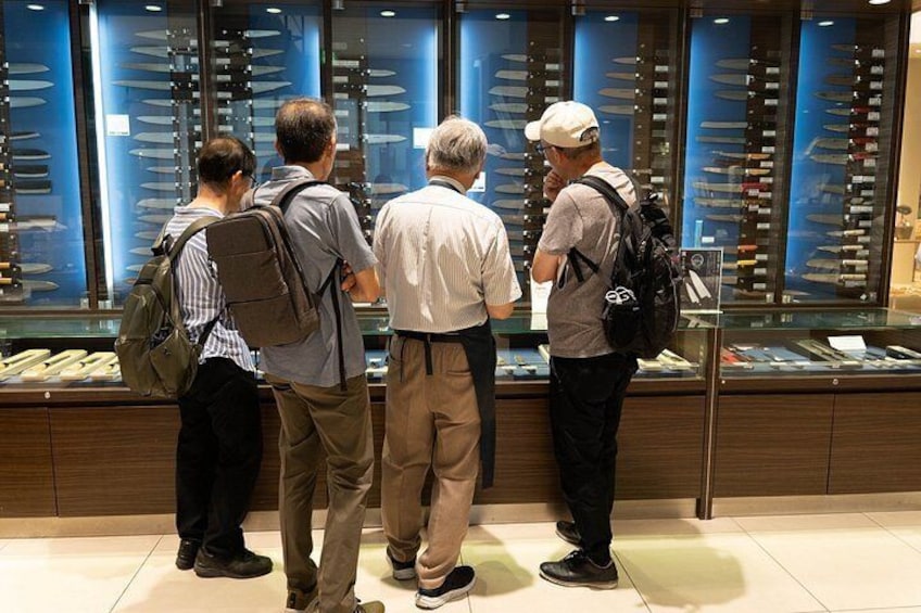 Four people examining a display of knives in a store. 3