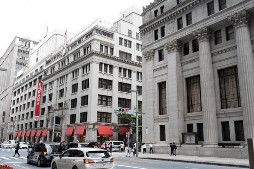 A city street with historic buildings, a red awning, and a parked car. 5
