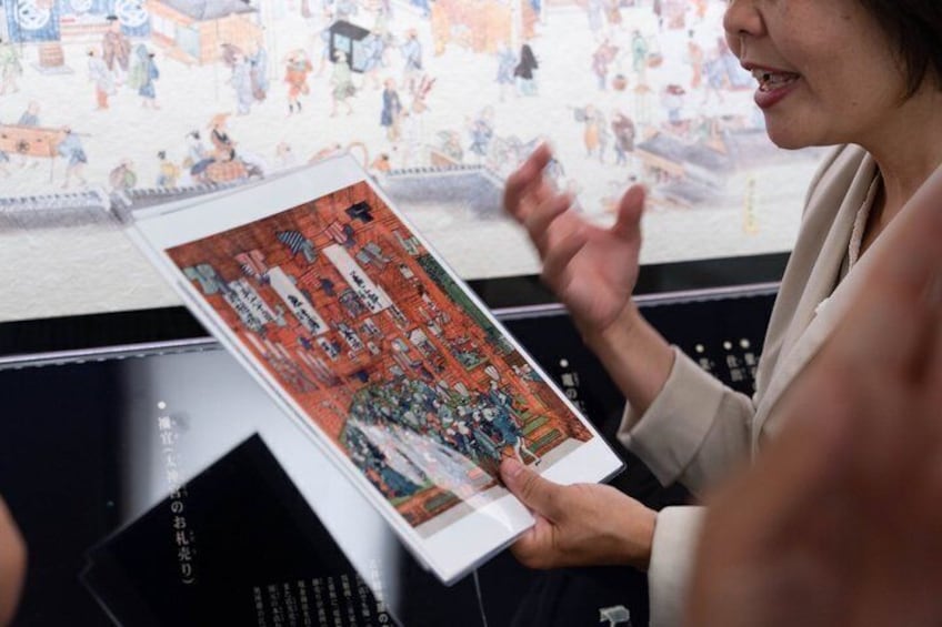 A person holding a book with a detailed illustration of a cityscape. 4