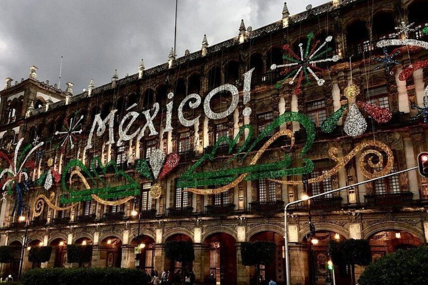 Un edificio con arquitectura ornamentada y decoraciones festivas, incluyendo un letrero grande que dice 'Mexico!'. 2