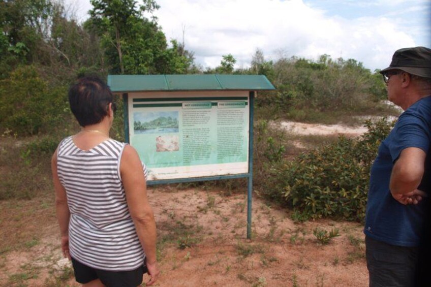 Two people standing in front of an informational sign in a natural setting. 3