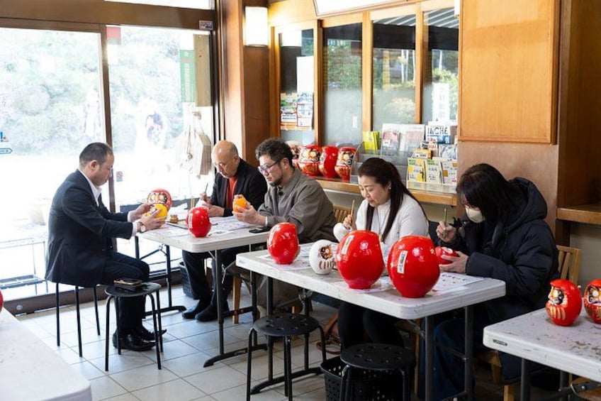 People sitting at tables with red balloons and food items. 1