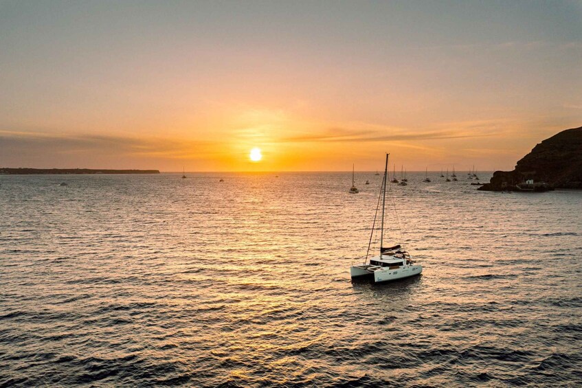 A sailboat anchored in calm waters during sunset. 4