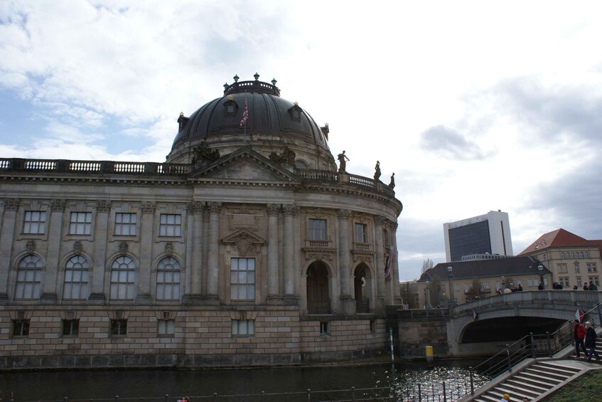 A historic building with a dome, a bridge, and a modern building in the background. 2