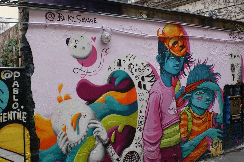 A colorful mural with abstract figures and graffiti tags. 3