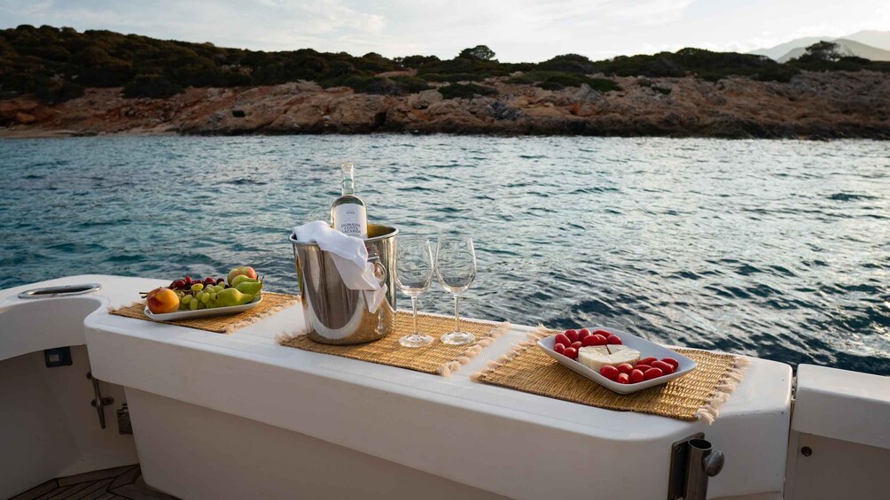 A boat with a table set for a meal, including fruits, cheese, and a bottle of wine. 4