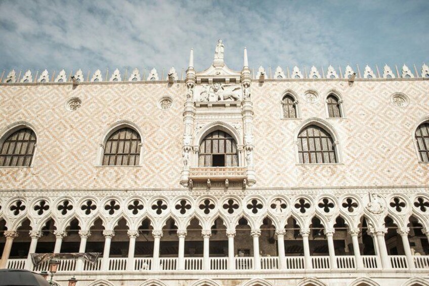 A building with a patterned facade, arched windows, and a series of arches along the ground floor. 3