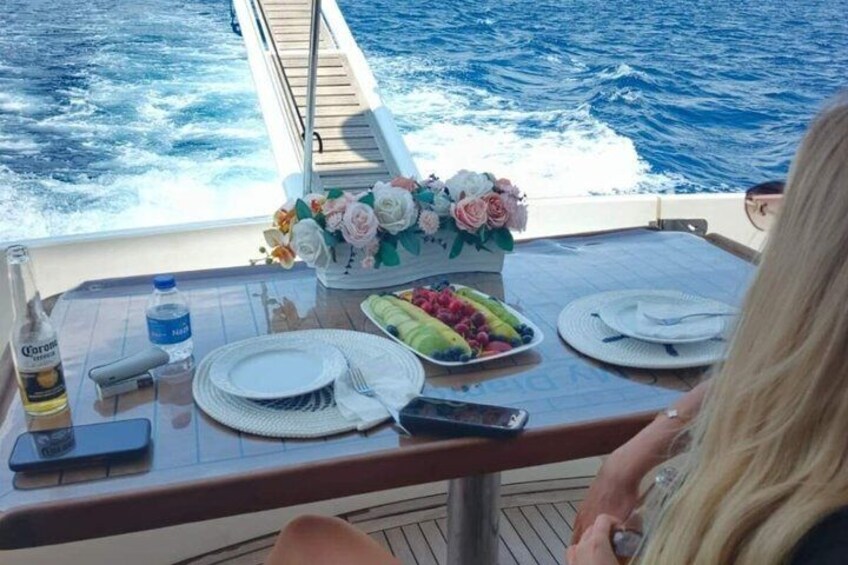 A dining table on a boat with plates, cutlery, a bottle, and a bouquet of flowers. 2