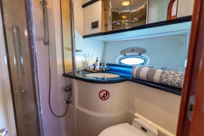 A compact bathroom with a glass shower enclosure, a sink with a towel, and a toilet. 3