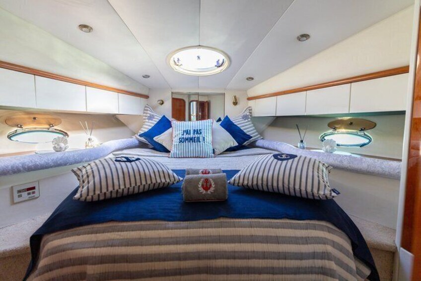 A cozy cabin interior with a bed, pillows, and a small table with a lamp. 4