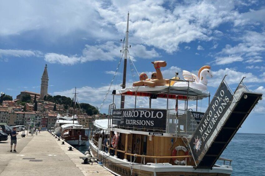 A boat named 'Marco Polo Excursions' docked at a pier with a cityscape in the background. 3