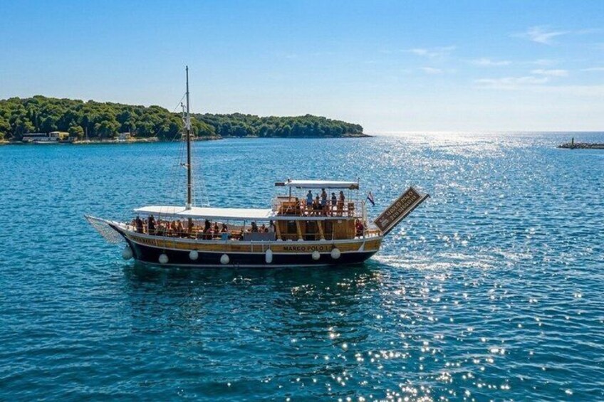 A boat named 'MARGARET' on a calm sea with a forested island in the background. 1