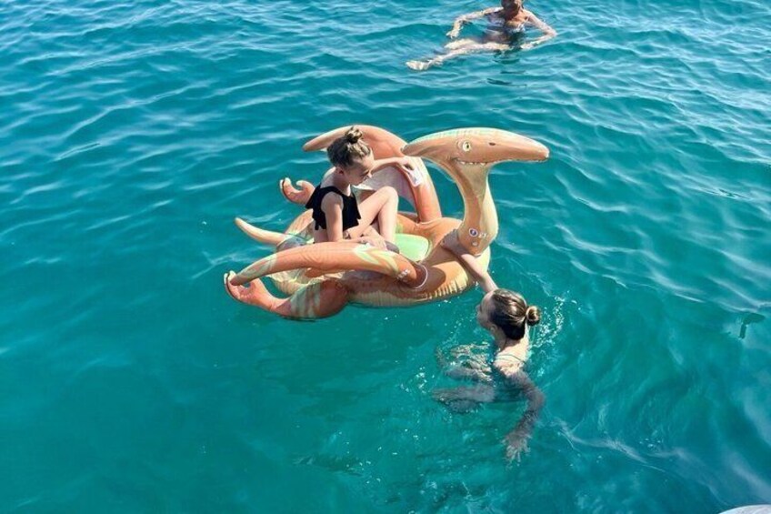 People floating on the water with an inflatable dinosaur float. 5